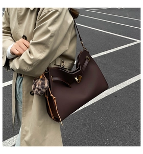 Detail of dark brown matte tote bag with drawstring closure and leopard print charm