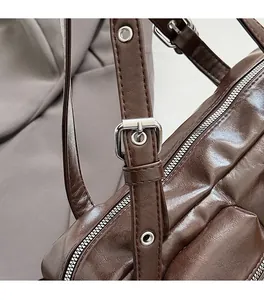 Close-up of adjustable silver buckle and smooth oil wax leather strap on a brown bag