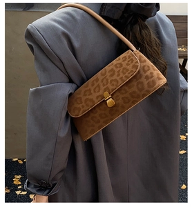 Detail der Baguette-Tasche mit Leopardenmuster und Goldschnalle an grauer Jacke