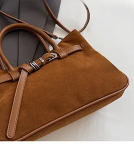 Detail of caramel suede baguette bag featuring silver buckle and fine edge stitching
