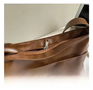 Detailed macro view of metal zipper and pocket hardware on a brown leather tote bag