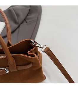 Detailed close-up of premium silver lobster clasp and stitching on brown suede bag