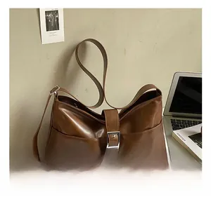 Detail view of the brown leather shoulder bag featuring a silver square buckle and smooth finish