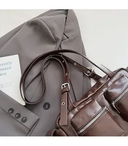 Detail of dark brown vintage motorcycle bag with functional pockets and silver zippers