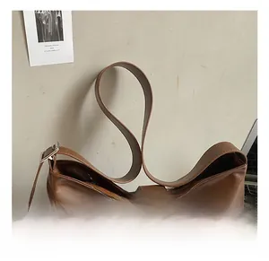 Detailed view of brown leather tote bag with silver buckle and side pocket feature