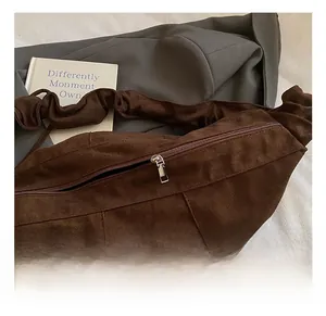 Close-up of dark brown suede dumpling bag featuring smooth silver metal zipper and soft texture