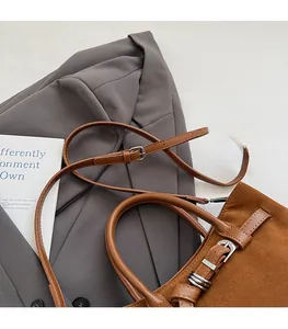 Detail of adjustable leather strap and silver buckle on brown suede baguette bag