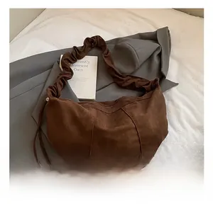 Macro shot of brown suede texture and pleated strap detail on the crescent bag