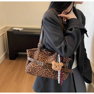 Detail of leopard print tote bag with brown leather strap and plush bear charm