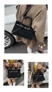 Close-up of matte suede bag texture with glossy leather trim and metallic buckle detail