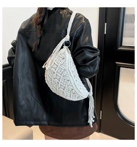 Close-up of white macrame half-moon bag with long tassels and woven shoulder strap