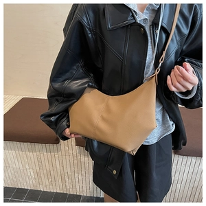 Détail du cuir synthétique grainé et des coutures verticales sur le sac bandoulière marron
