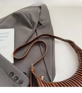 Close-up of brown pleated shoulder bag with adjustable strap and golden zipper detail
