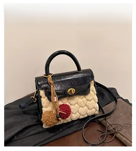 Detail of heart-patterned faux fur bag with golden twist lock and pom-pom charm