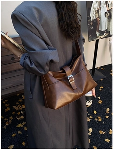 Detailed side view of a brown leather shoulder bag with a stylish silver metal buckle