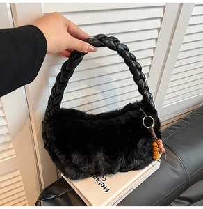 Detail of black plush handbag featuring braided faux leather handle and beaded charm