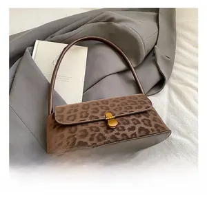 Detail view of leopard print shoulder bag with golden buckle on grey blazer