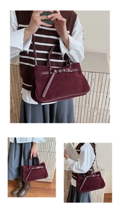 Detail view of the burgundy suede baguette bag featuring buckle strap and versatile shoulder strap