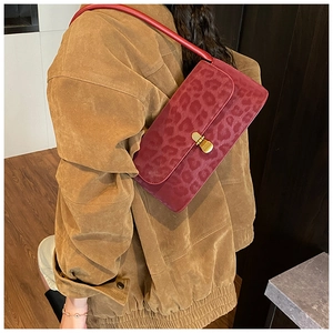 Detail view of burgundy leopard print shoulder bag with gold metal twist lock buckle