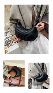 Detailed view of black vertical pleated cloud bag with adjustable strap and matte finish