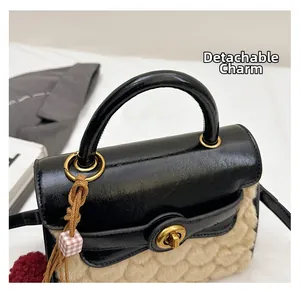 Detail of shearling and black leather bag with gold handle and removable charm