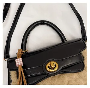Detail of black glossy leather handbag with brown faux fur bottom and gold twist lock