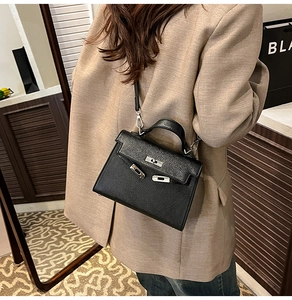 Vista detallada del bolso cruzado de cuero negro estilo retro combinado con blazer.