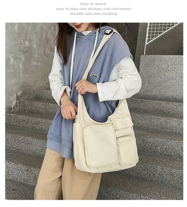 Detail view of large cream canvas tote bag with multiple pockets and wide strap