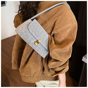 Close-up of gray leopard print shoulder bag with vintage gold buckle on a model