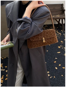 Detail of leopard print shoulder bag with golden twist lock on autumn ginkgo leaves