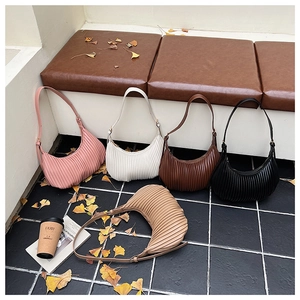 Detailed view of half-moon pleated hobo bags in five colors with autumn decorations