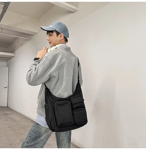 Détail du sac fourre-tout en toile noire montrant plusieurs poches et un tissu résistant