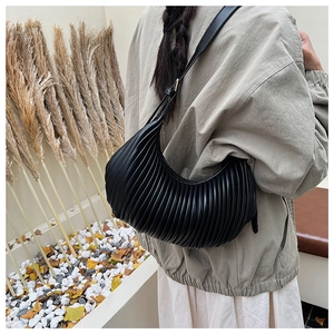 Side view of black pleated dumpling bag worn by model in an autumn aesthetic setting