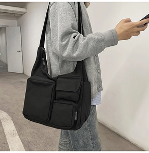 Détail du sac cabas en toile noire avec plusieurs poches et une large bandoulière