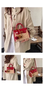 Detail of red leather and heart embossed plush handbag with gold twist lock and fur pom poms