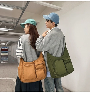 Détail de sacs bandoulière en toile vert armée et brun orange avec plusieurs poches pratiques