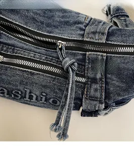 Detail of vintage denim crossbody bag featuring double zippers and yellow stitching