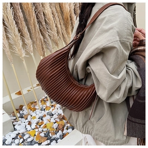 Close-up of brown pleated crescent shoulder bag with elegant texture in outdoor setting