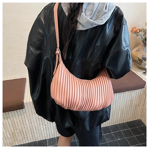 Pink pleated hobo bag shown in a styled lifestyle setting worn with a leather jacket