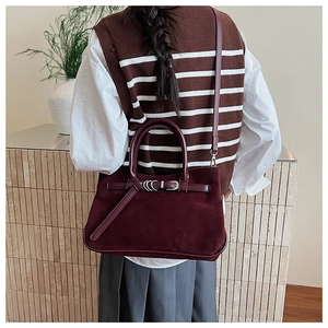 Detail of burgundy faux suede handbag featuring vintage metal ring buckle and dual handles