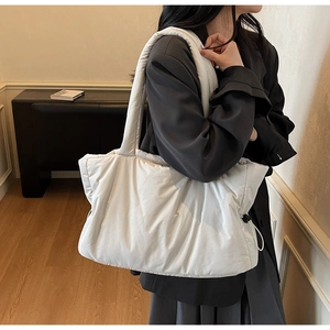 Detail of white quilted tote bag with side drawstring and padded texture in a minimal setting