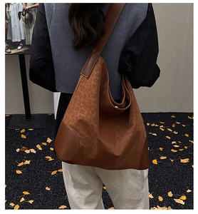 Leopard print tote bag with brown leather trim shown on a model in autumn leaves scenery