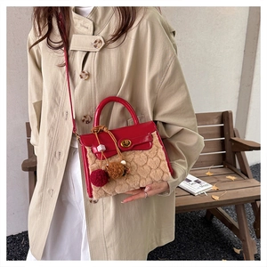 Detail of red leather and beige faux fur crossbody bag with golden clasp on a trench coat