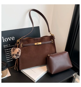 Detail of vintage brown suede tote bag featuring a gold twist-lock and leopard print charm