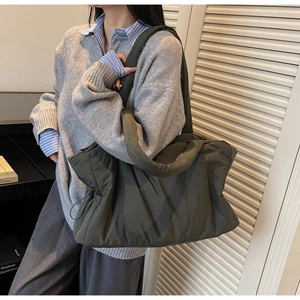 Detail of dark olive green puffy nylon tote bag with drawstring and thick shoulder strap