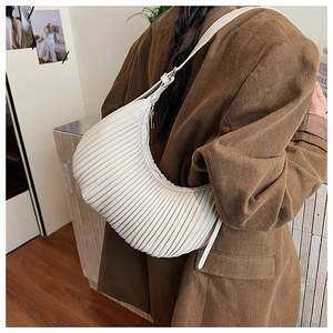 Detail of cream pleated hobo bag showing accordion texture and adjustable shoulder strap