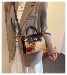 Detail view of lambswool Kelly bag with gold twist-lock and plush bicolor ball charm