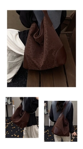 Detail of vintage leopard print tote bag with brown leather accents on a wooden bench
