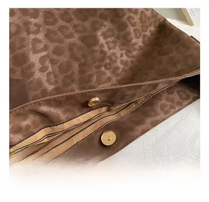 Detail showing the leopard print satin fabric and golden magnetic clasp of the tote bag