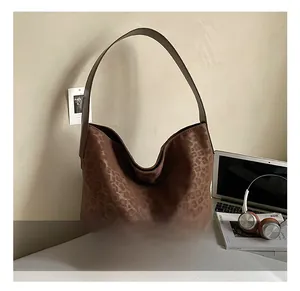 Detail of leopard print tote bag with brown leather strap in a lifestyle office setting